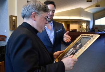 Armusik, right, gifts Bishop Alfred Schlert with his painting “Agony in the Garden” of Jesus praying in the Garden of Gethsemane. Armusik presented the gift to Bishop Schlert prior to the Serra dinner honoring the Diocese’s newly ordained Father John Hutta June 18 at St. Mary. (Photo by John Simitz)