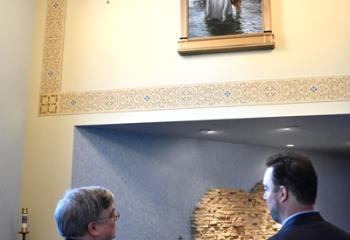 Bishop Schlert, left, and Armusik discuss Armusik’s “Baptism of Christ” as the Bishop admires the painting. (Photo by John Simitz)